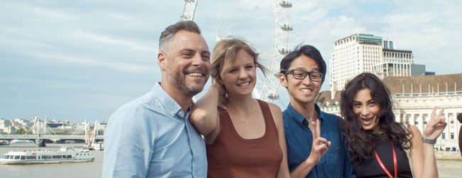 Vier Menschen posieren für die Kamera im Hintergrund die Themse und London Eye