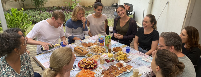 Mehrere Sprachreiseteilnehmer geniessen ein reichhaltiges Frühstück mit tropischen Früchten und Gebäck auf La Réunion