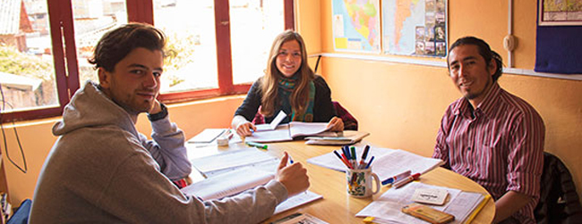 Drei Erwachsene beim Gruppenunterricht an einem Tisch während einer Sprachreise für Erwachsene in Peru