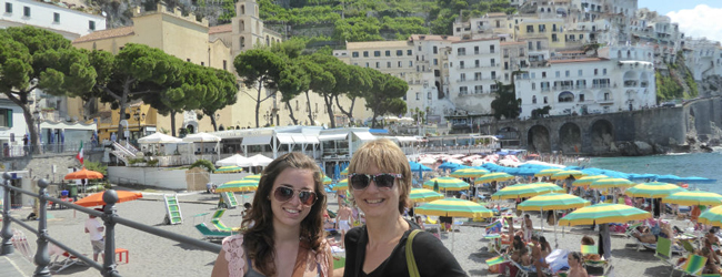 Mutter und Tochter am Strand von Amalfi mit bunten Sonnenschirmen und historischen Gebäuden im Hintergrund während einer LISA! Sprachreise