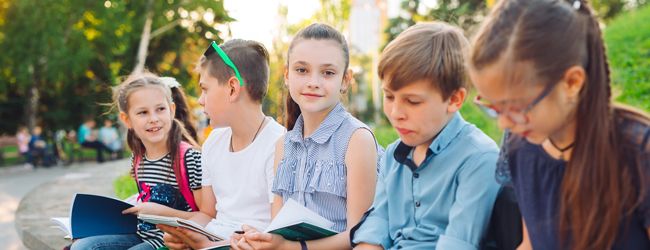 Mädchen und Jungen sitzen draussen und lernen Englisch gemeinsam während einer Sprachreise für Schüler in Box Hill