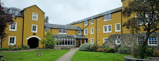 Gelbes Gebäude mit Garten und Bäumen in Edinburgh Loretto