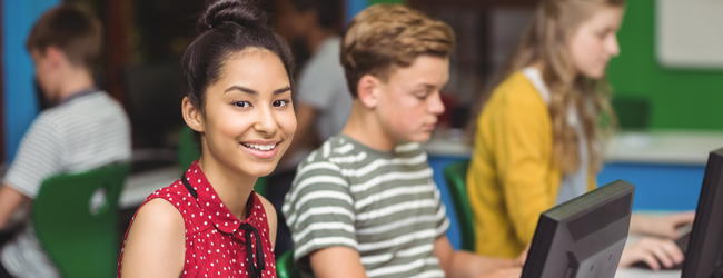 Junge Mädchen sitzt lächelnd am Computer in einem modernen Klassenzimmer bei einer LISA! Schülersprachreise in Los Angeles