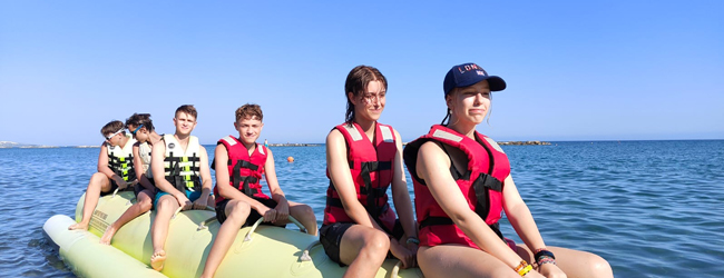 Mehrere Jugendliche sitzen auf einem Bananenboot im Meer auf Zypern bei einer LISA! Schülersprachreise