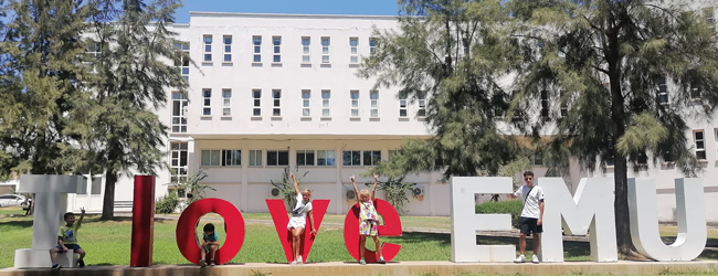 Kinder stehen zwischen grossen Buchstaben vor der Universität in Famagusta