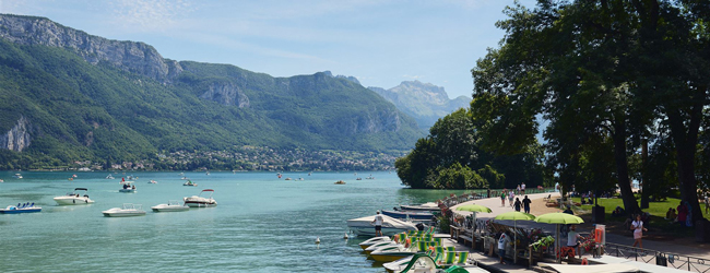 Blick auf den türkisblauen Bergsee in Annecy mit Bergen im Hintergrund und Booten