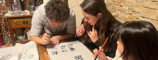 Ein Lehrer zeigt zwei Schülern die Schriftzeichen Japanisch bei einer Schülersprachreise in Tokio