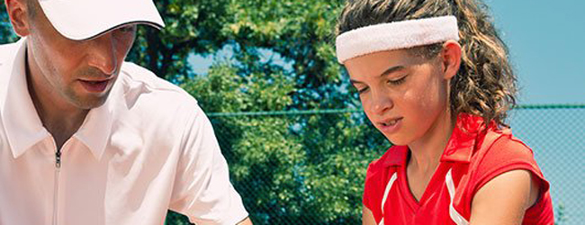 Schülerin beim Tennistraining auf einem Tennisplatz mit Trainer während einer Sprachreise in Nottingham